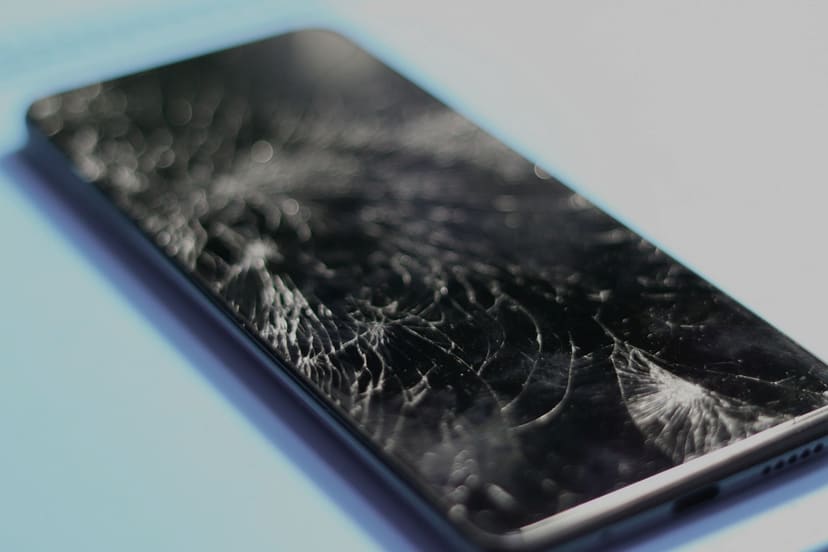 Mobiltelefon med knust skjerm, sett på skrå i nærbilde.